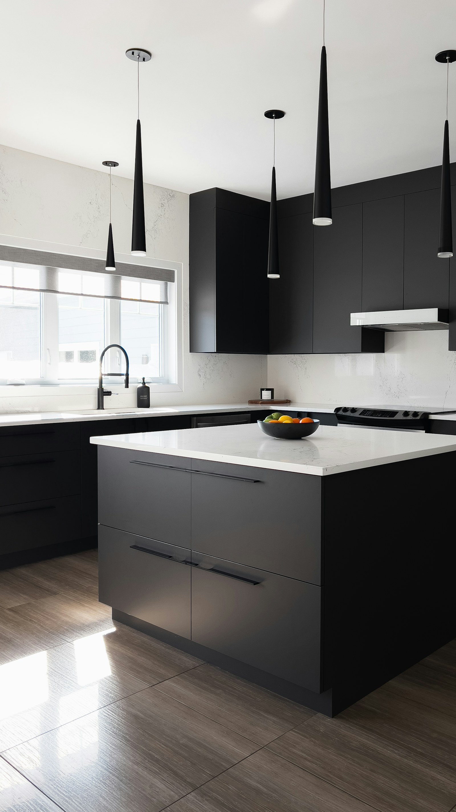A matte-black kitchen with quartz countertops and a built-in range, photographed in soft afternoon light.