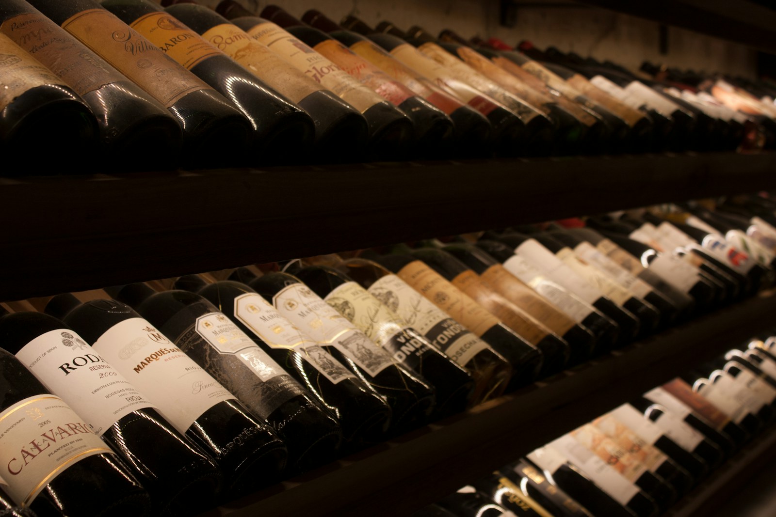 A working cellar — long racks of vintage bottles in low warm light.