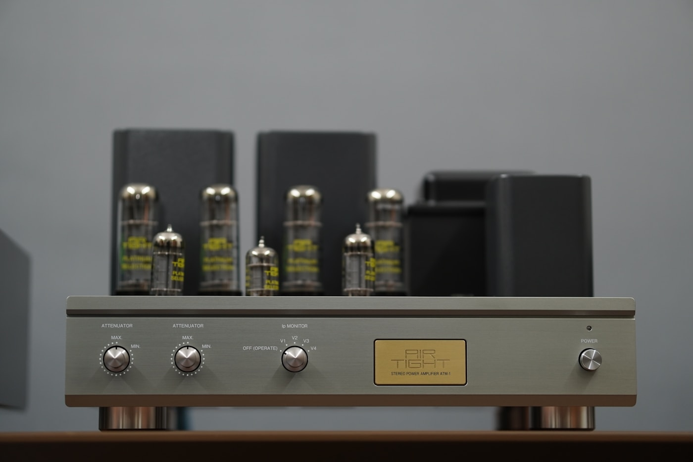 A vacuum-tube stereo amplifier in brushed steel and brass, photographed in warm tungsten light.