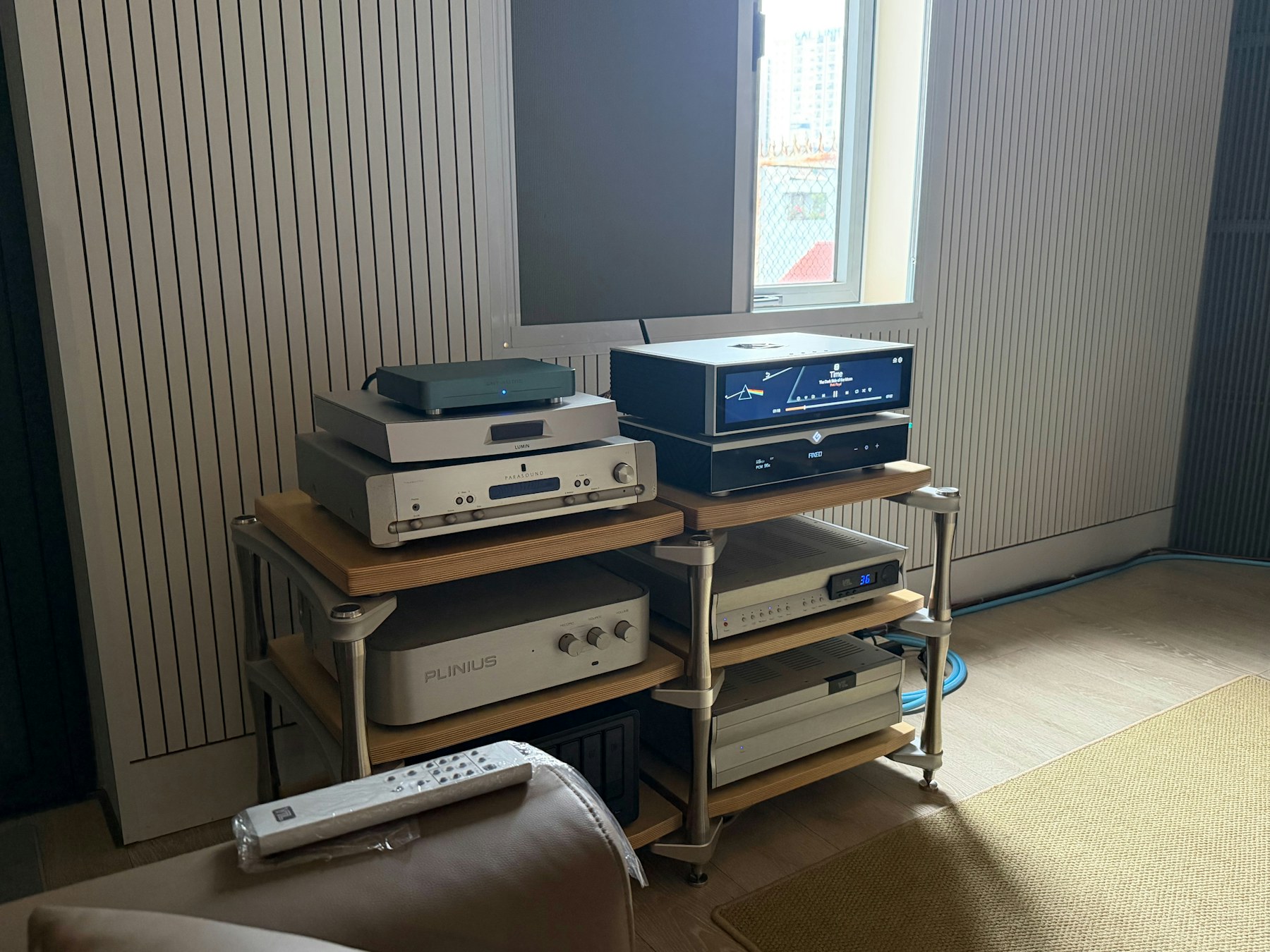 A domestic hi-fi rack with stacked amplifiers, transports, and a turntable in warm afternoon light.
